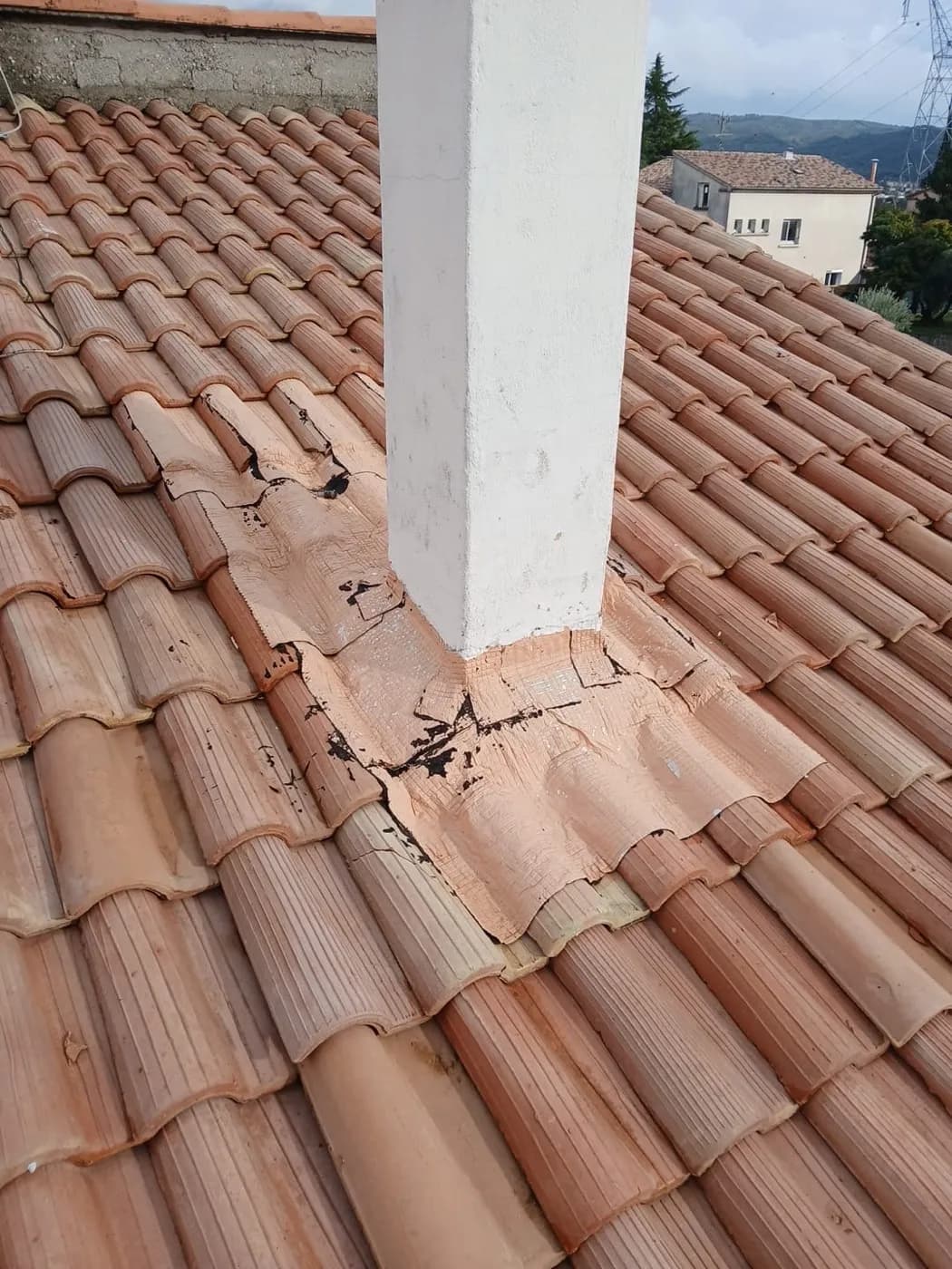 Souche de cheminée étanchée au mastic craquelé, tuiles fendues tout autour