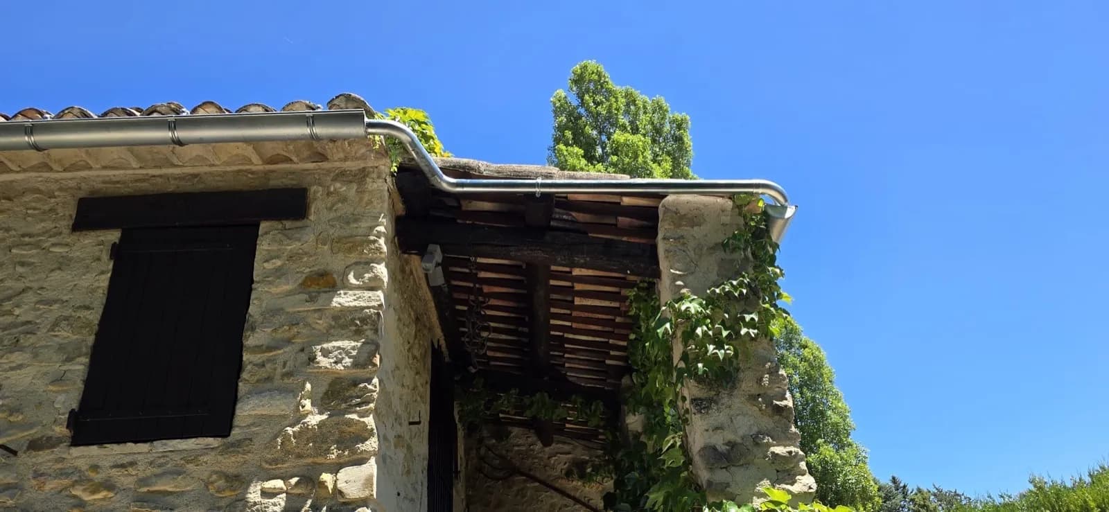 Angle de gouttière en zinc au-dessus d'un auvent à charpente ancienne