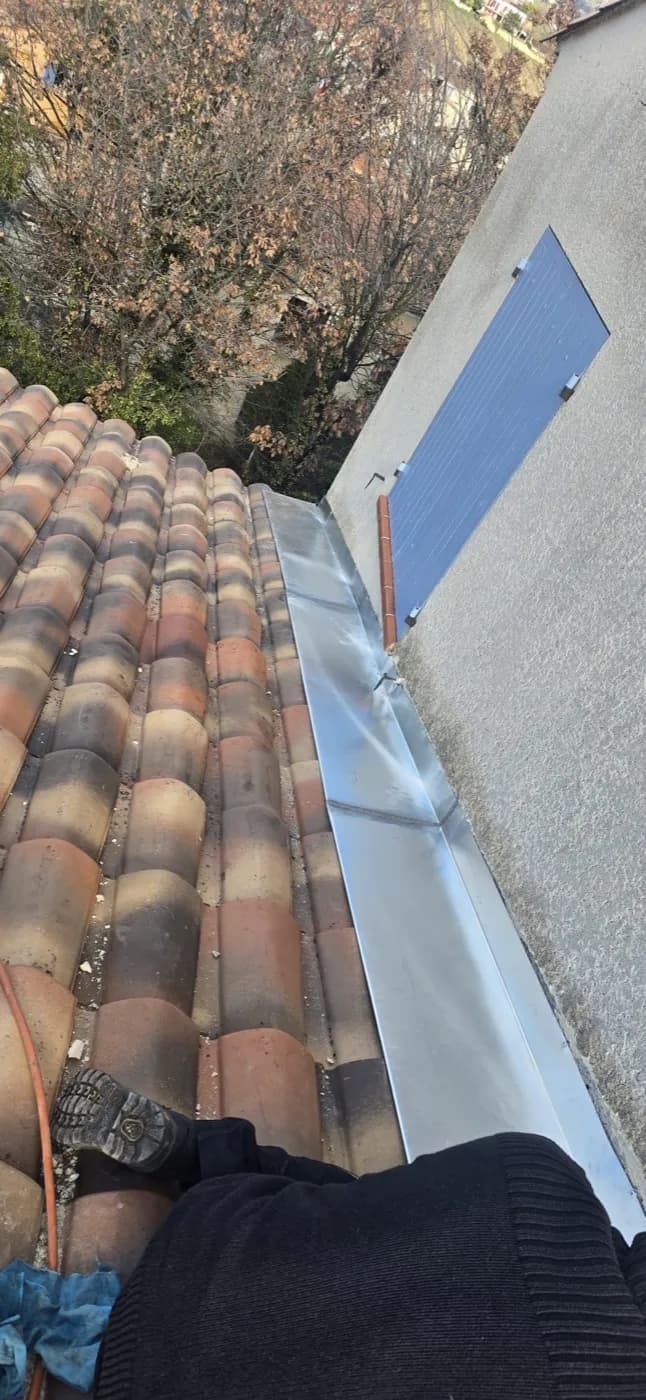 Bande de solin en zinc posée le long d'un mur, contre une rive de tuiles