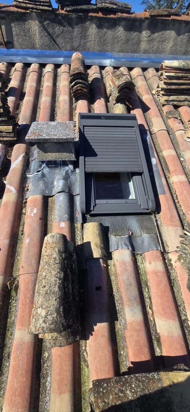 Fenêtre de toit avec volet roulant et raccord en zinc, sur de vieilles tuiles canal